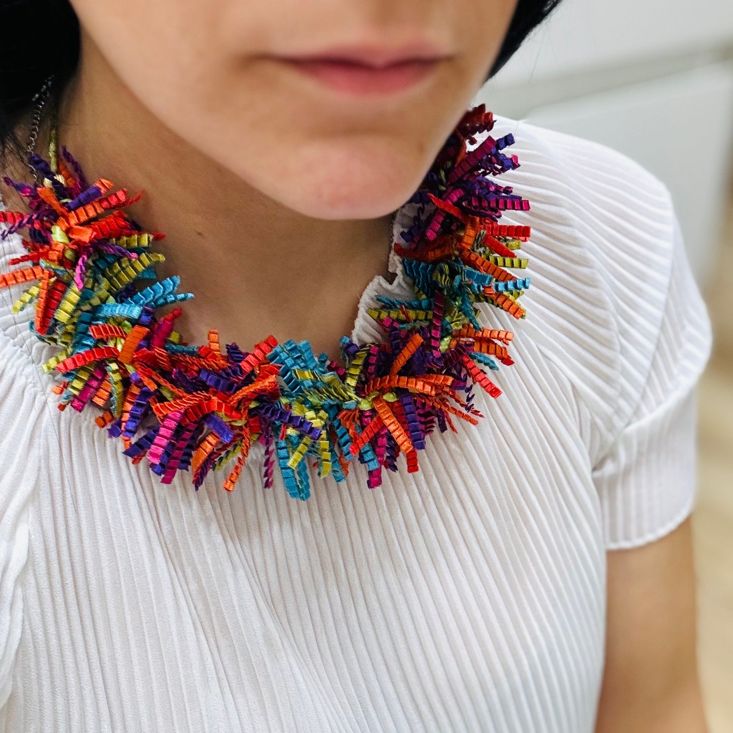un primo piano di una donna che indossa una collana colorata