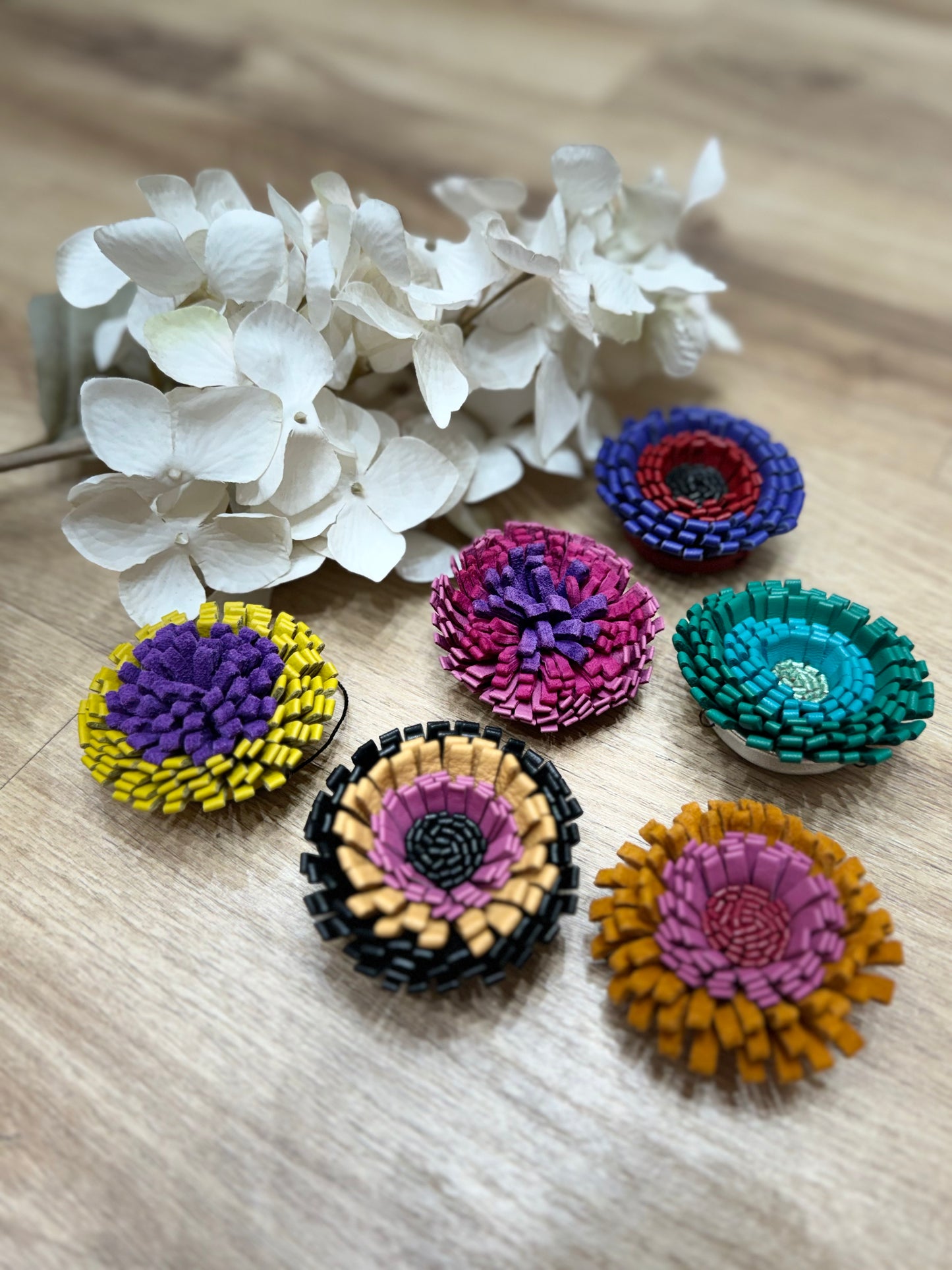 un mazzo di fiori posato su un tavolo di legno con varie spille in pelle