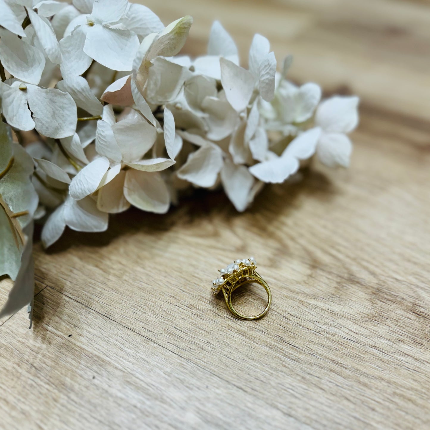 un anello appoggiato su un tavolo di legno accanto ai fiori