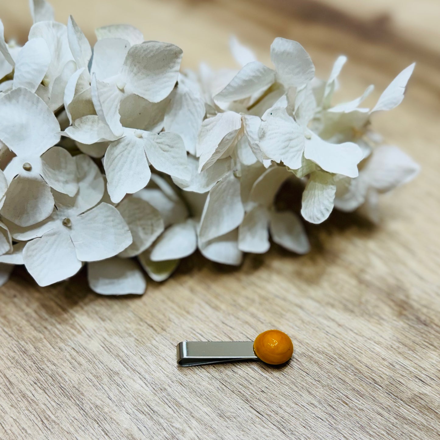 un fiore bianco ed un fermacravatta su un tavolo di legno