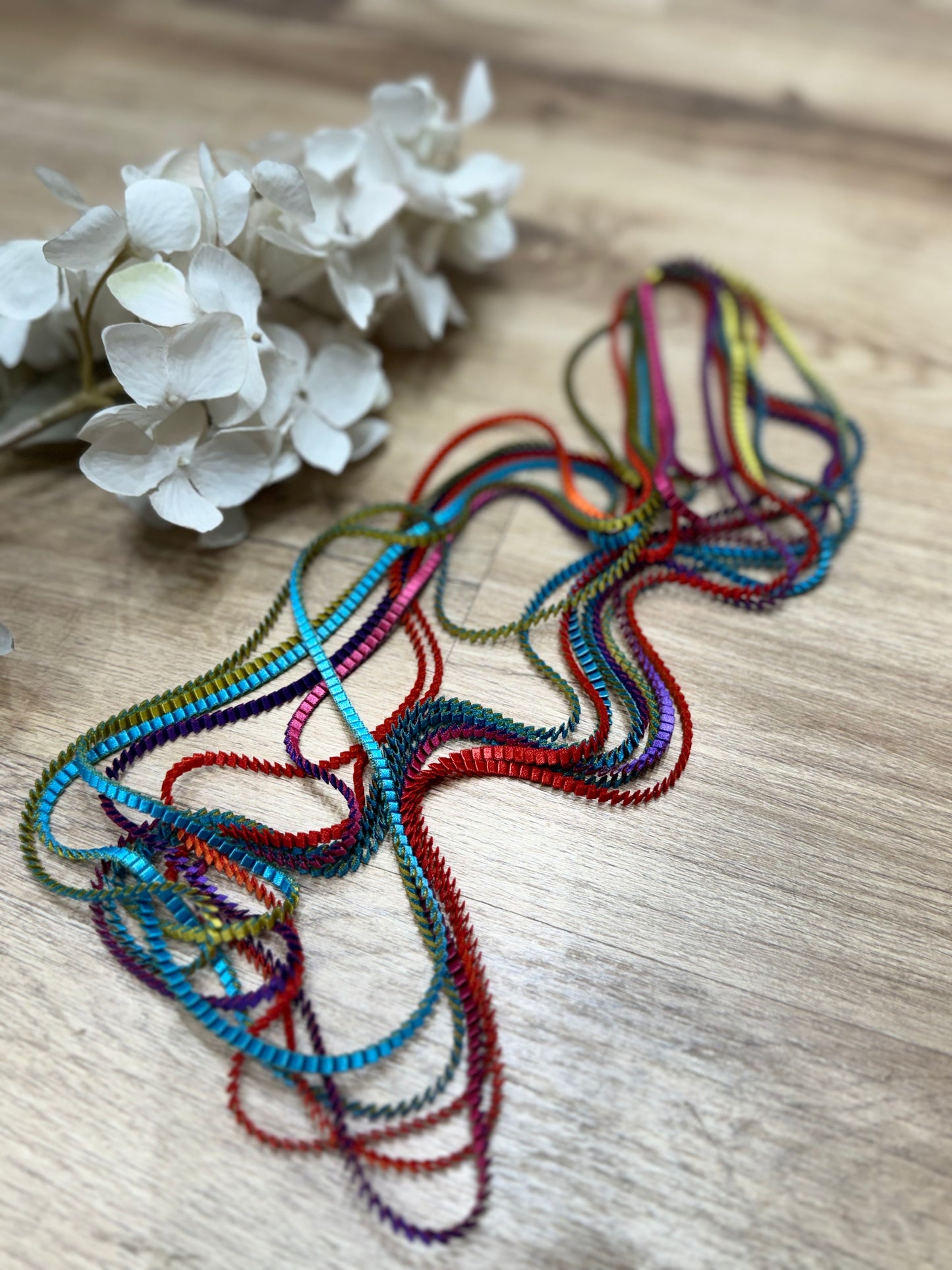 un primo piano di un fiore su un tavolo ed una collana multicolore