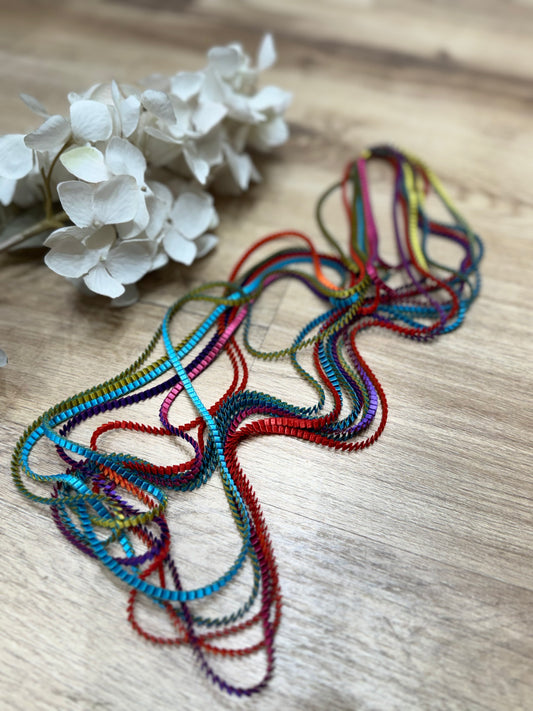 un primo piano di un fiore su un tavolo ed una collana multicolore