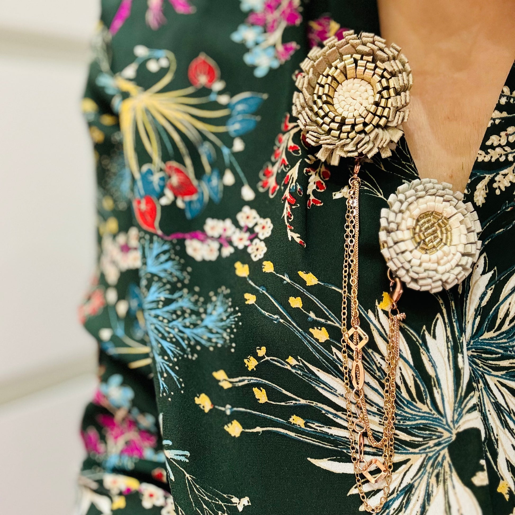 un primo piano di una persona che indossa una camicia floreale con aggiunta di una spilla