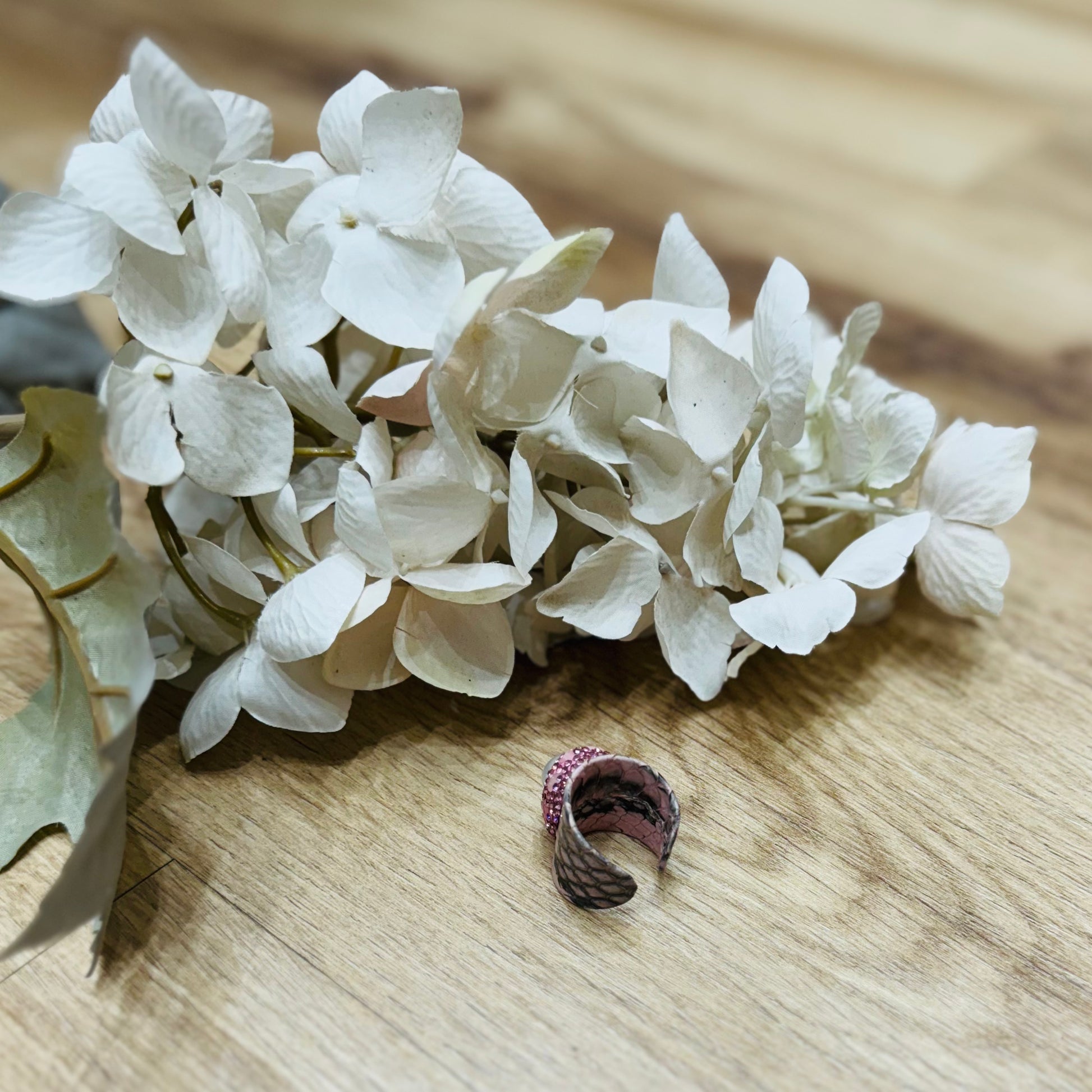 un mazzo di fiori bianchi poggiato su un tavolo di legno con vicino un anello