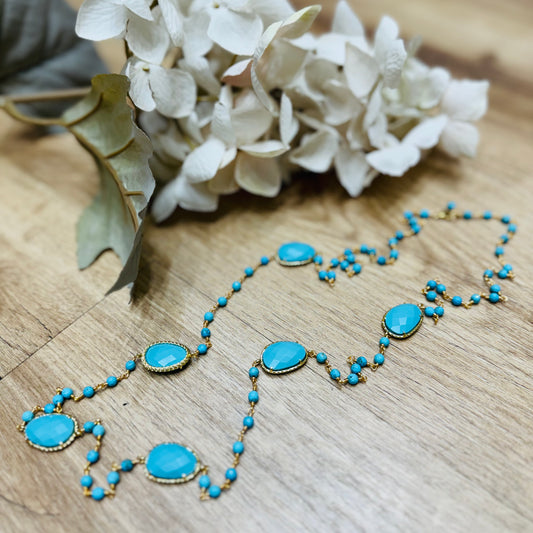 una collana con perline blu e un fiore su un tavolo