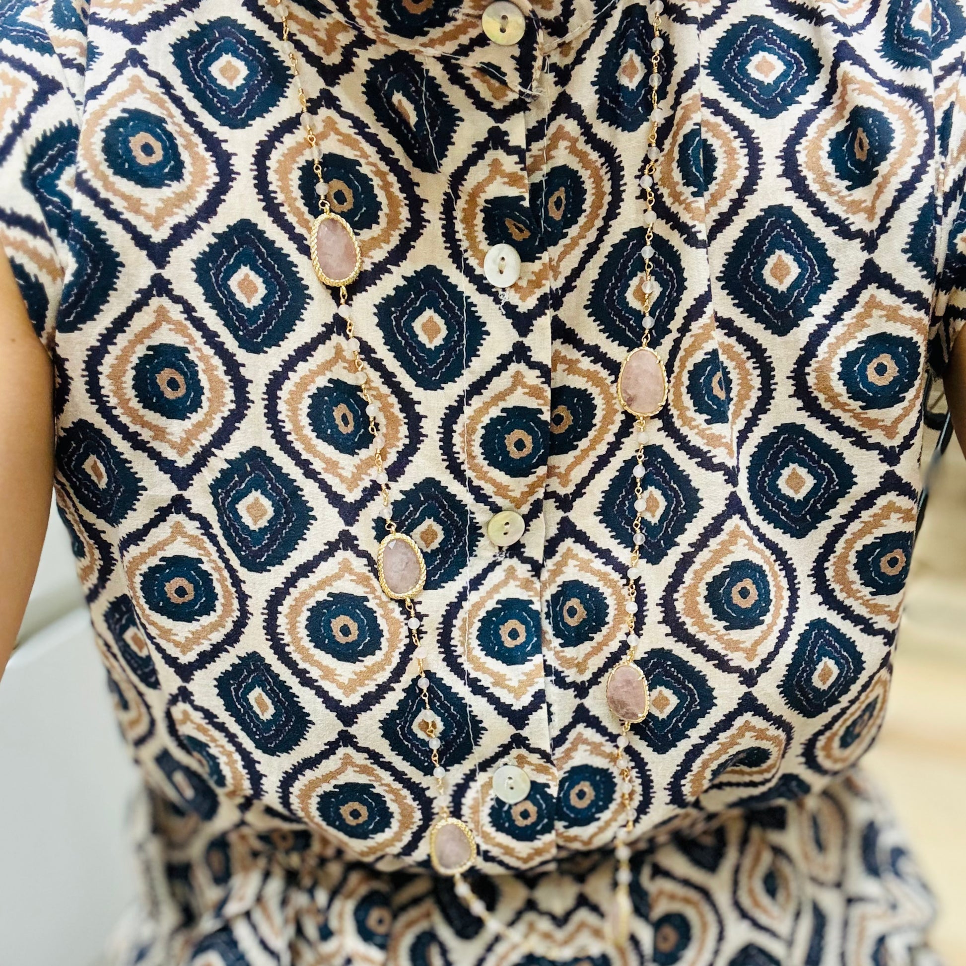 un primo piano di una persona che indossa una camicia fantasiosa ed una collana