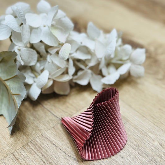 un braccialetto posato su un tavolo di legno accanto a dei fiori