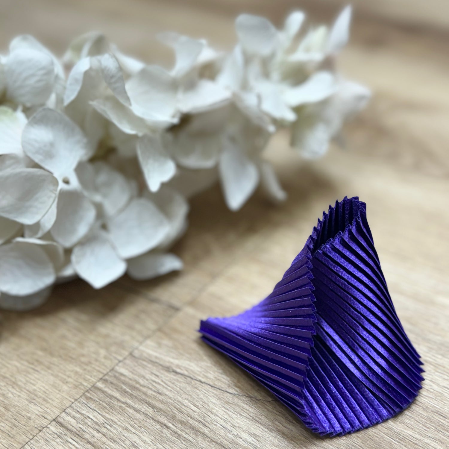 Un braccialetto viola accanto a dei fiori bianchi