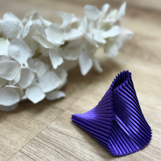Un braccialetto viola accanto a dei fiori bianchi