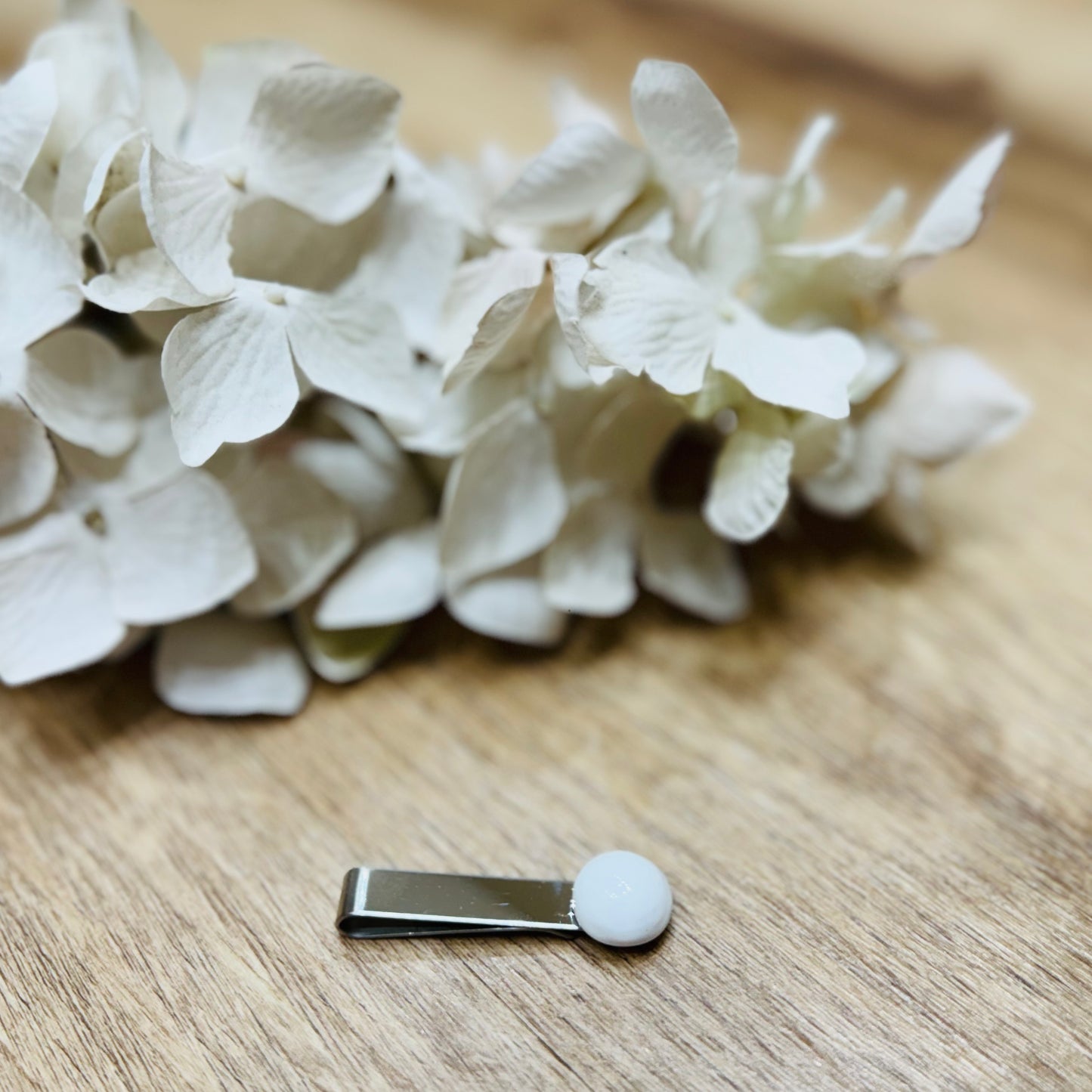 Un fermacravatta colorato vicino ad un fiore bianco su un tavolo di legno