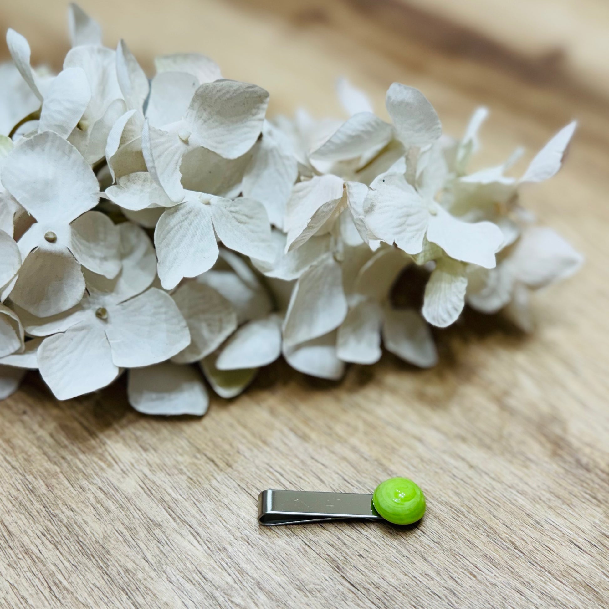 Un fermacravatta colorato vicino ad un fiore bianco su un tavolo di legno
