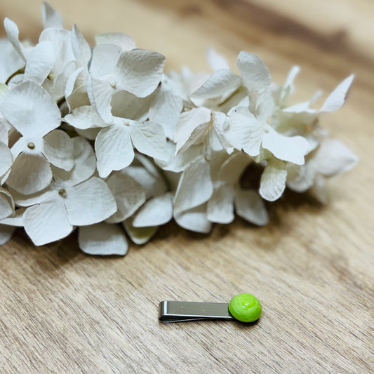 Un fermacravatta colorato vicino ad un fiore bianco su un tavolo di legno