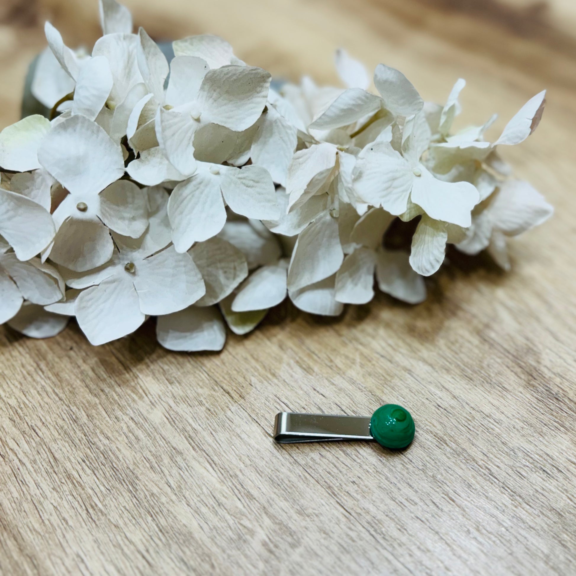 Un fermacravatta colorato vicino ad un fiore bianco su un tavolo di legno