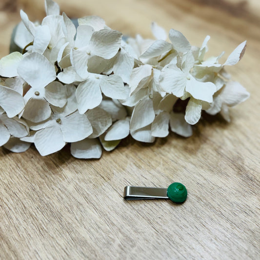 Un fermacravatta colorato vicino ad un fiore bianco su un tavolo di legno